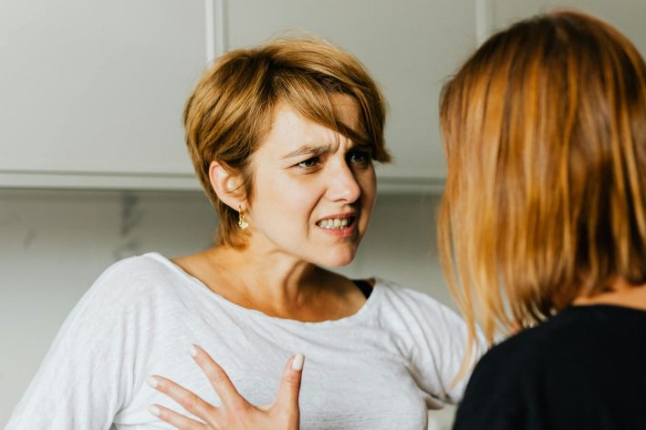 Two women engaged in a heated discussion in a modern kitchen.